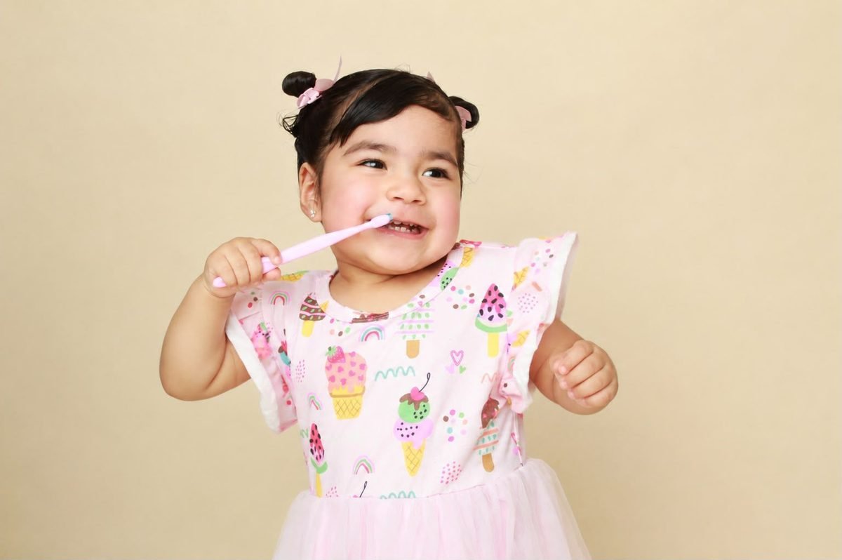 Niña sonriendo mientras se cepilla los dientes